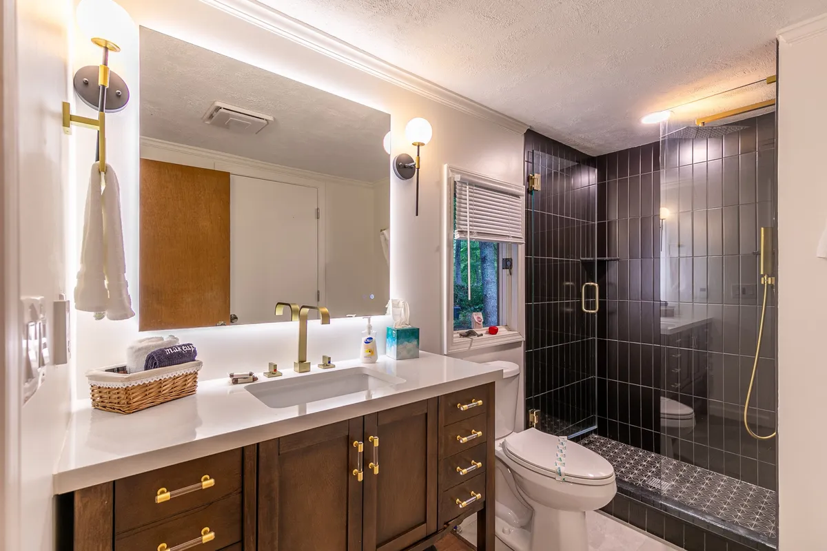 A fresh and inviting bathroom featuring a vanity with a well-lit mirror, modern sink, and a spacious shower area. The design blends functionality with a spa-like atmosphere, making it ideal for personal routines and relaxation.