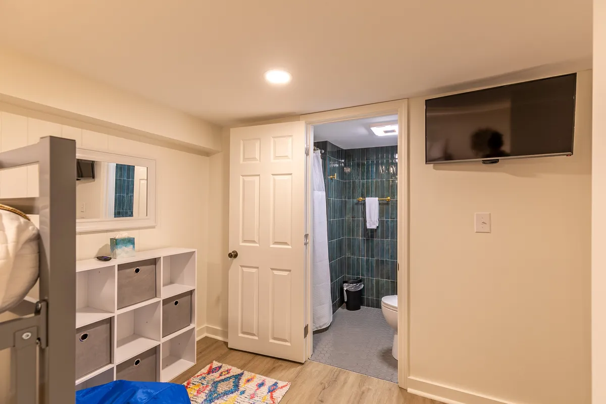 A cozy bunk room with a bunk bed, storage unit, and entertainment options, designed for kids or guests. The space looks functional yet inviting, perfect for sleepovers, movie nights, or group fun.