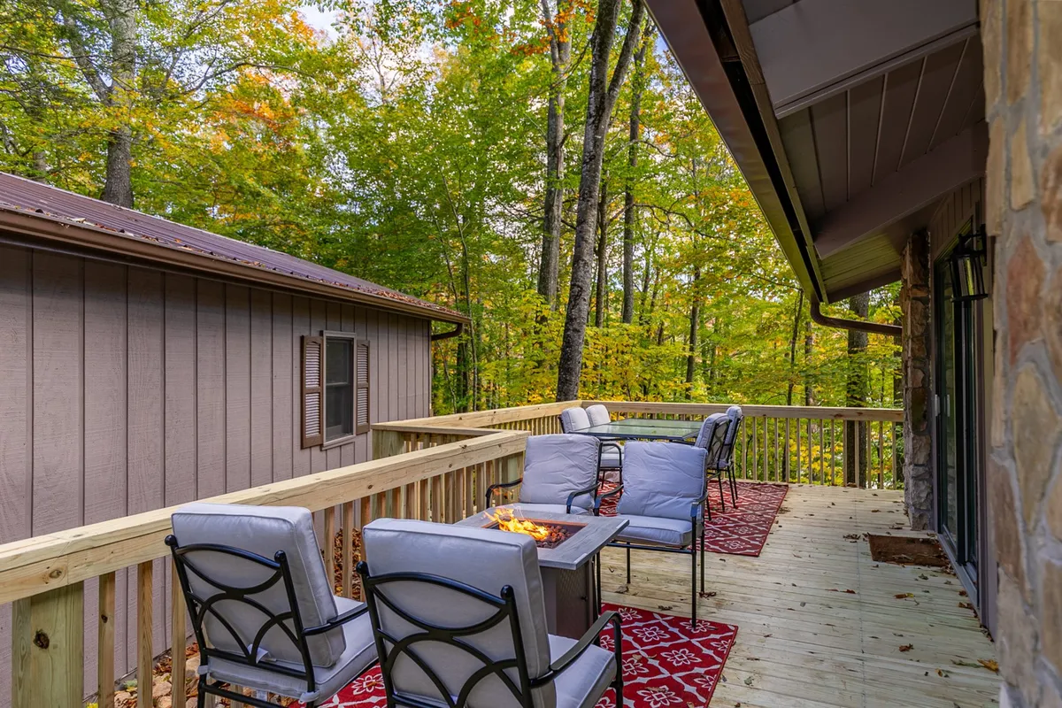 A tranquil outdoor space with a wooden deck, seating area, fire pit, and lush greenery. The setup encourages cozy mornings with coffee, serene nature walks, and sociable evenings around the fire pit—perfect for unwinding after outdoor pursuits.